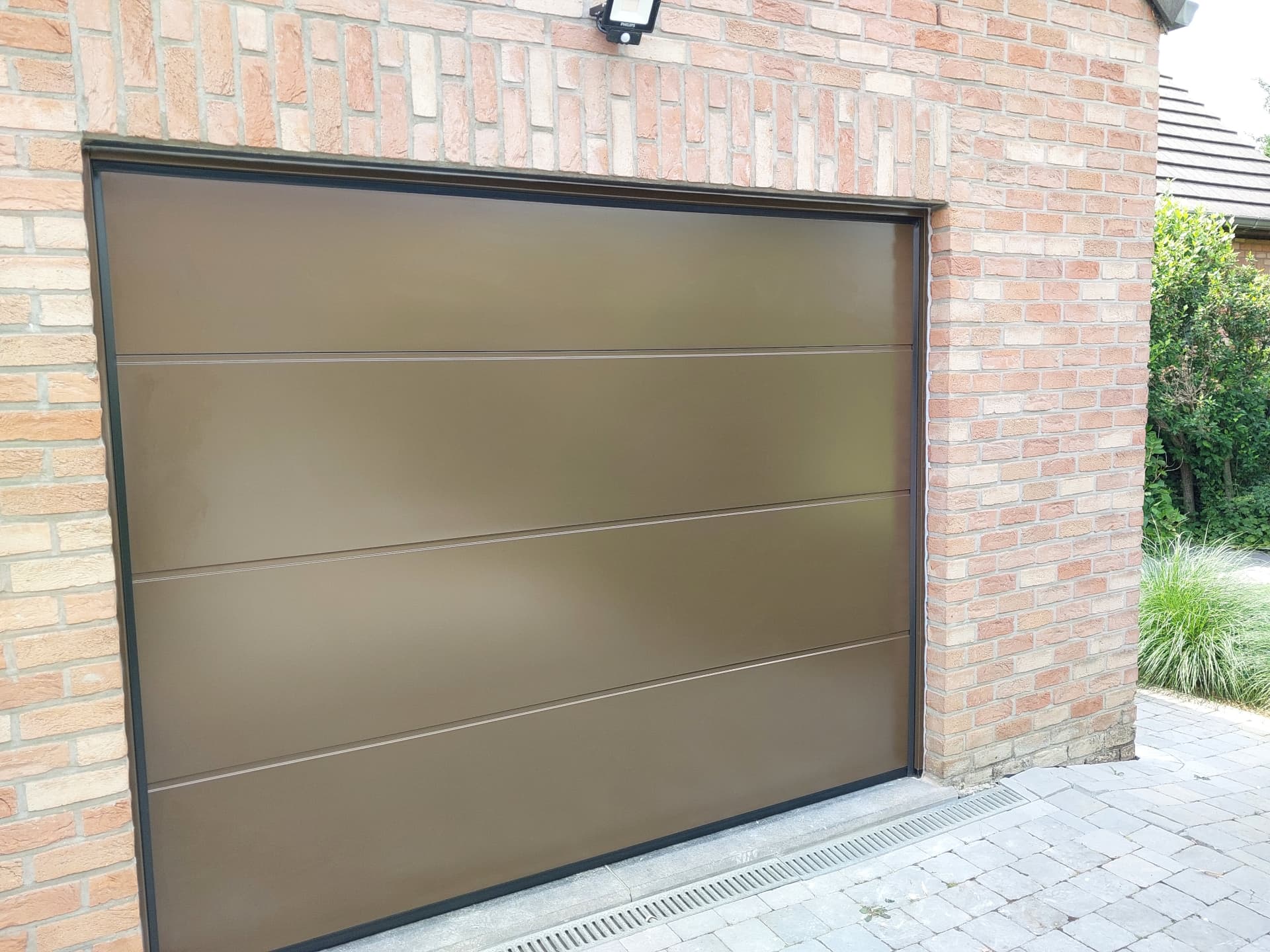 Porte de garage sectionnelle bronze sur maison en briques