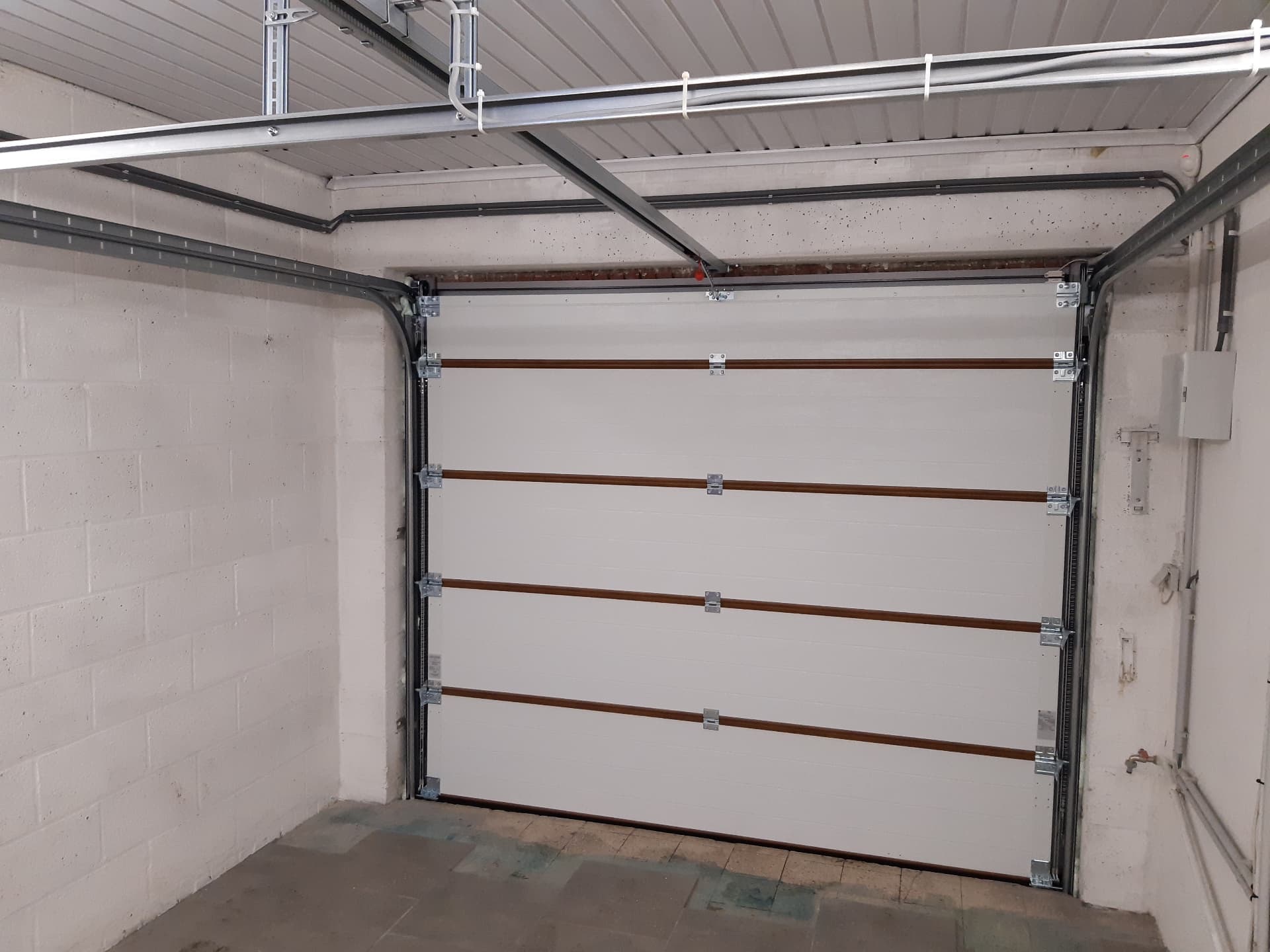 Porte de garage sectionnelle blanche vue de l'intérieur avec rails plafond