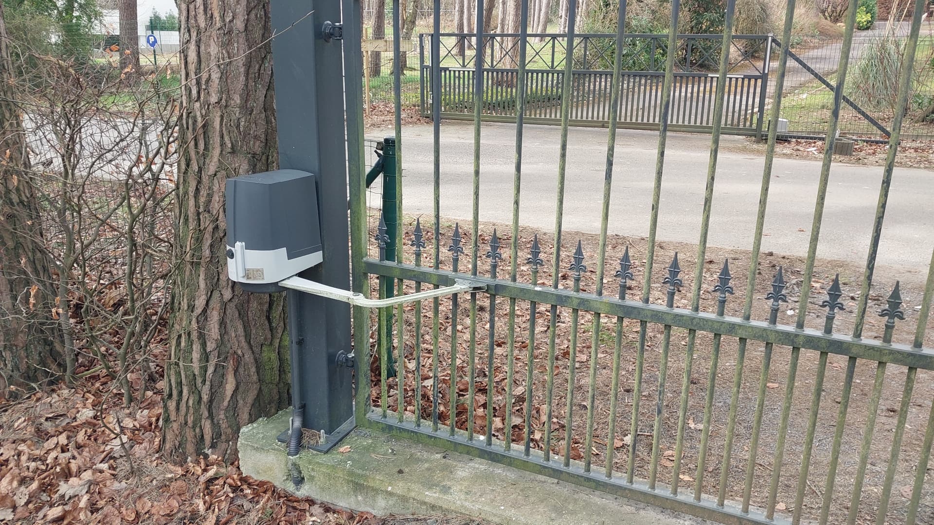 Moteur à bras articulé installé sur le pilier d'un portail battant